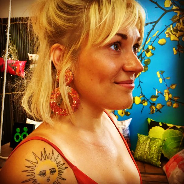 A woman with a tattoo on shoulder wearing round earrings 