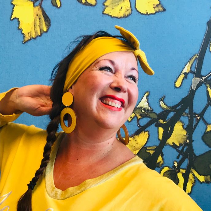 Happily smiling woman wearing yellow hoop earrings and yellow shirt 